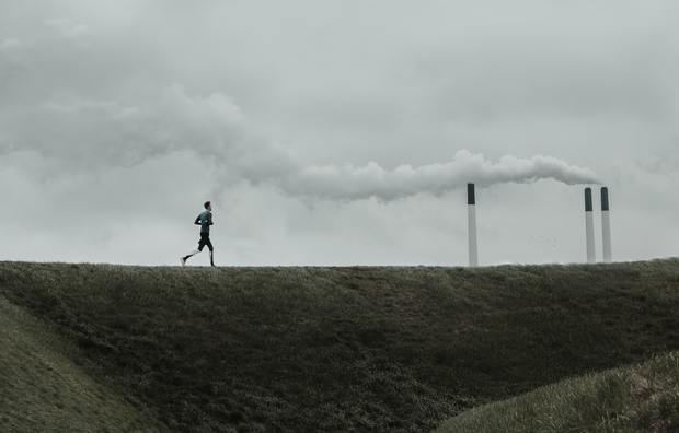 Man jogging in front of air pollution
