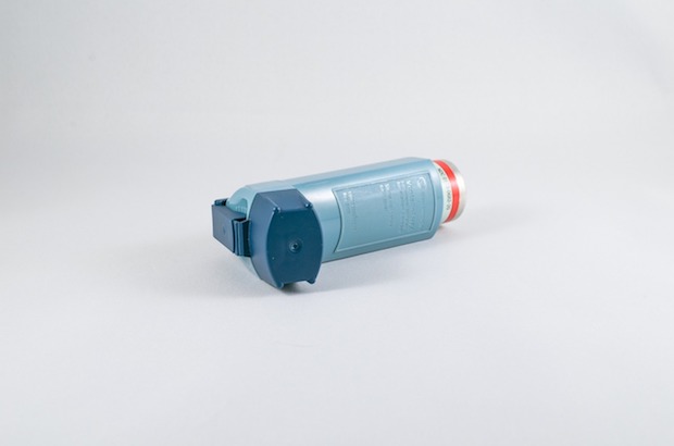 An asthma inhaler lying on its side on a plain background